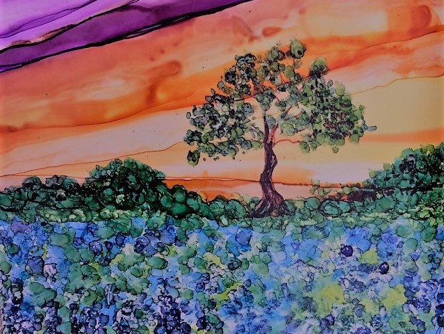 Alcohol ink tile art of a field of bluebonnets against an orange sunset, with a tree in the center of the work.