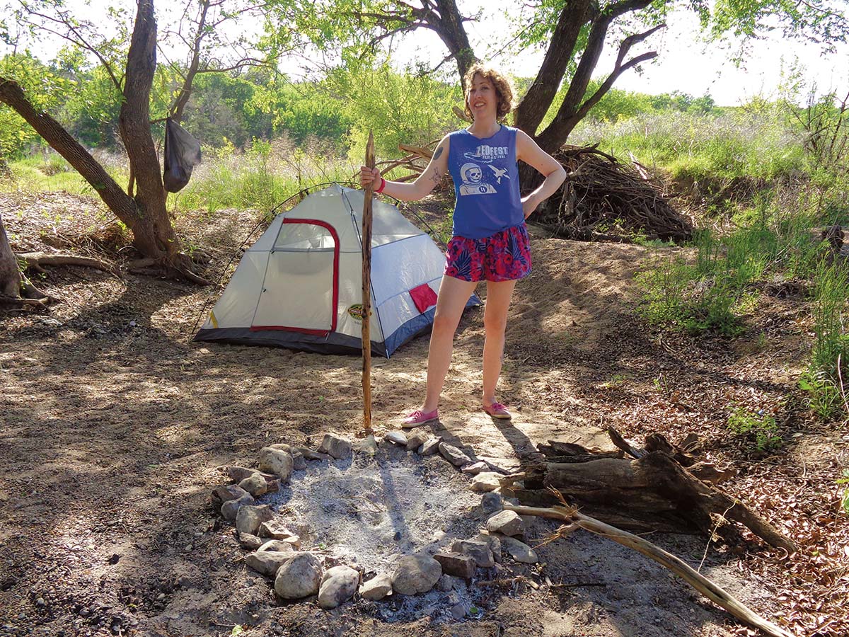 Wildflower magazine editor Amy McCullough shows off her sandbar-island campsite, a wooden staff inherited from a previous camper, and a handcrafted fire ring. PHOTO Jimmie Buchanan Jr.