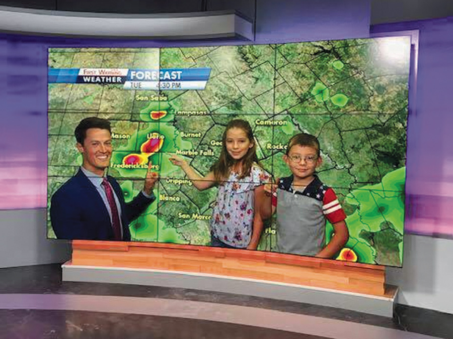 Two young children point to highlighted areas on a weather map as they are learning about meteorology with David Yeomans, a central Texas meteorologist.
