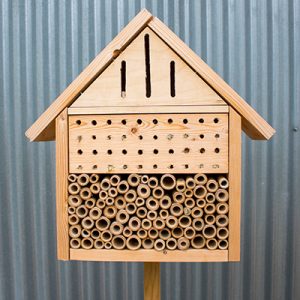 A wooden bee house with a corrugated steel shed behind it.