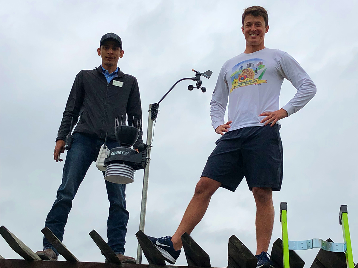 Meteorologist David Yeomans standing next to the weather station that he donated and helped install at the Wildflower center. Leo Hernandez is on his left. It was a grey and cloudy day.