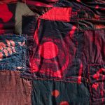 A variety of fabric cyanotypes showing the outline of plants overlaid with red and stitched together.