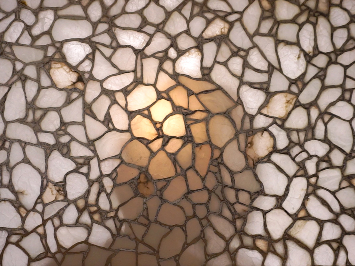 A video still featuring a white mosaic with someone's shadow in the middle of it